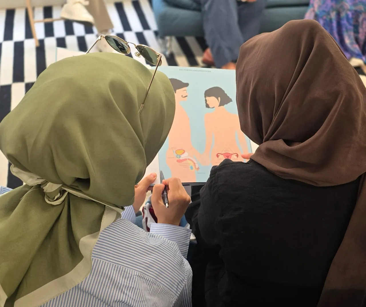 Two participants looking at an illustration of the reproductive system